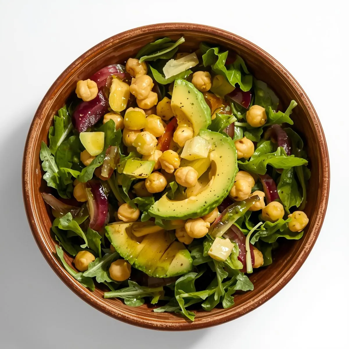 A colorful salad bowl with fresh greens, chickpeas, avocado, and vinaigrette